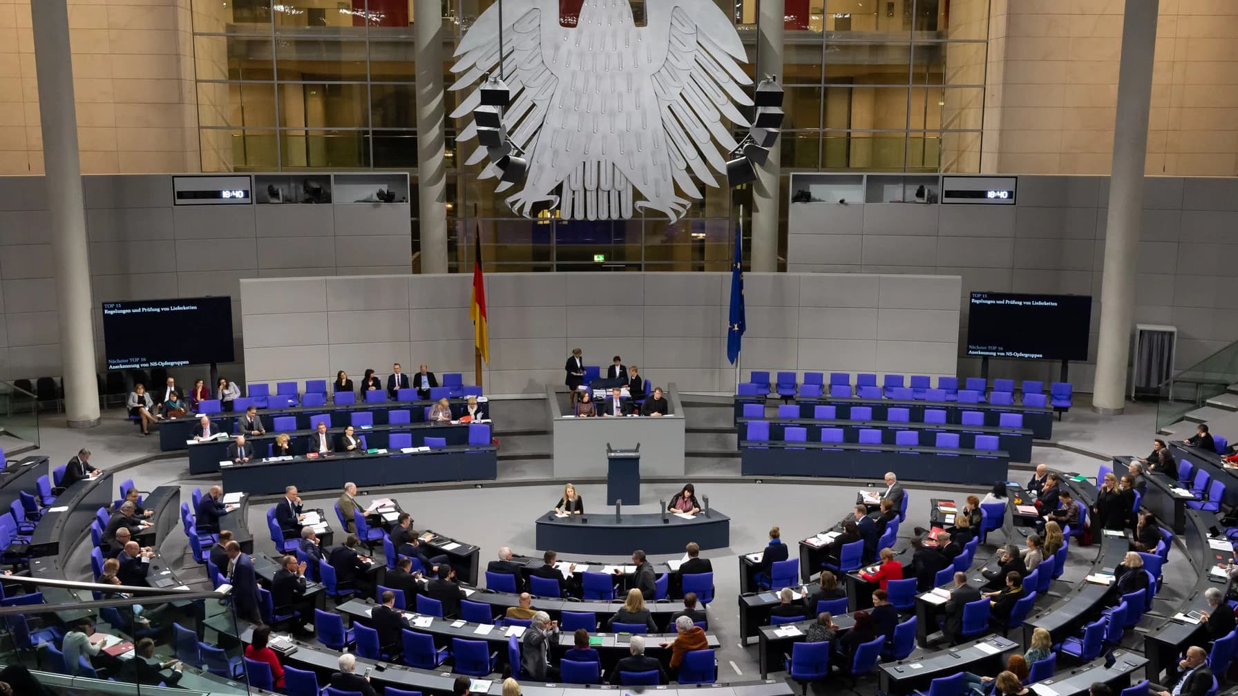 Blick in den Plenarsaal des Deutschen Bundestages während einer Sitzung, die Abgeordneten sitzen in Blöcken, dahinter der Bundesadler